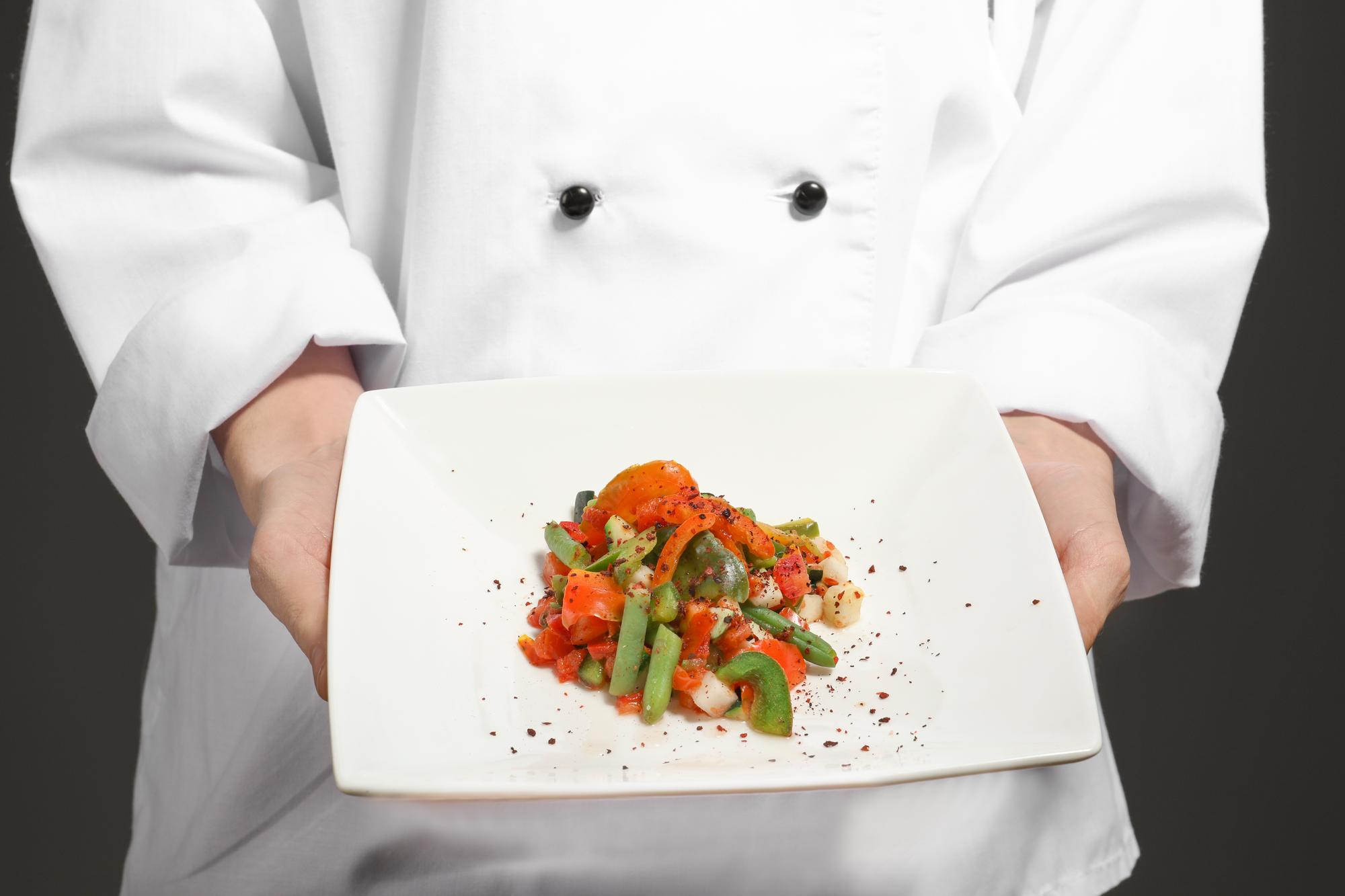 Hands preparing plated dish on wooden table